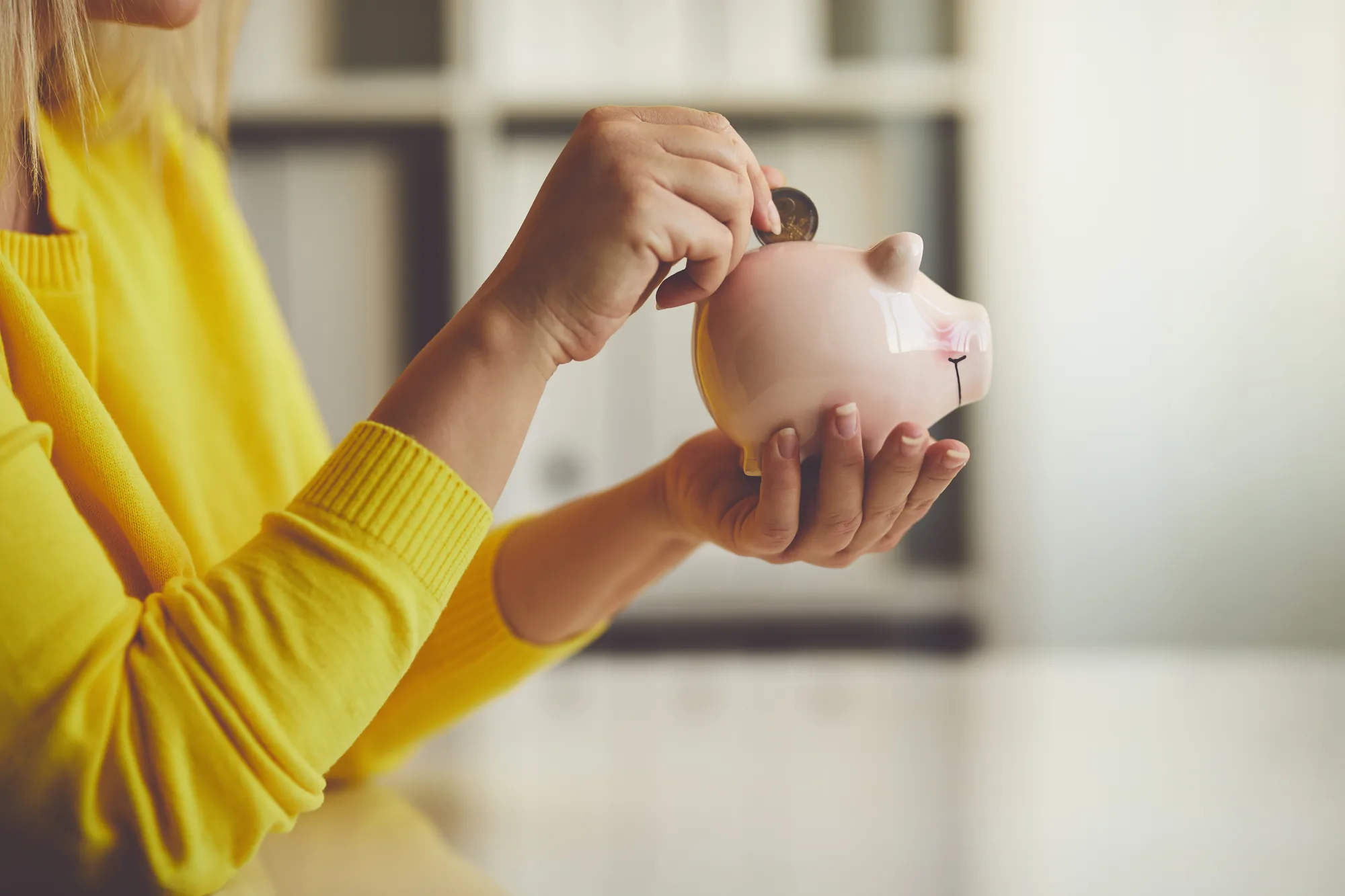 Member dropping a coin into a piggy bank, building her savings a little at a time